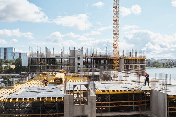 Commercial construction site showing formwork installation with tower crane and worker on multi-story building