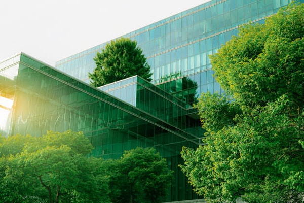 Modern green glass commercial building with sustainable landscaping and contemporary architecture