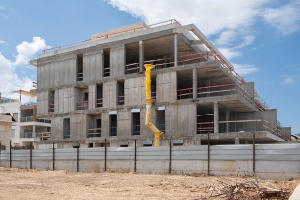 Multi-story concrete building under construction with yellow crane on site
