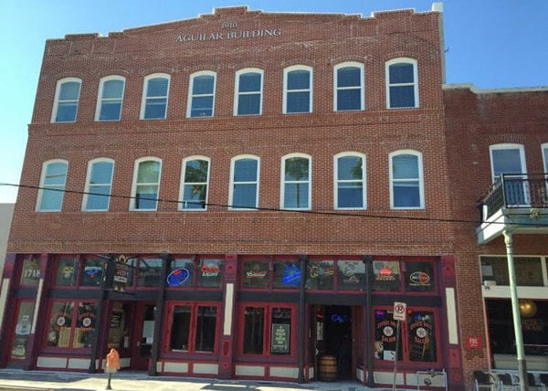 Three-story historic brick commercial building with flat roof and red storefront