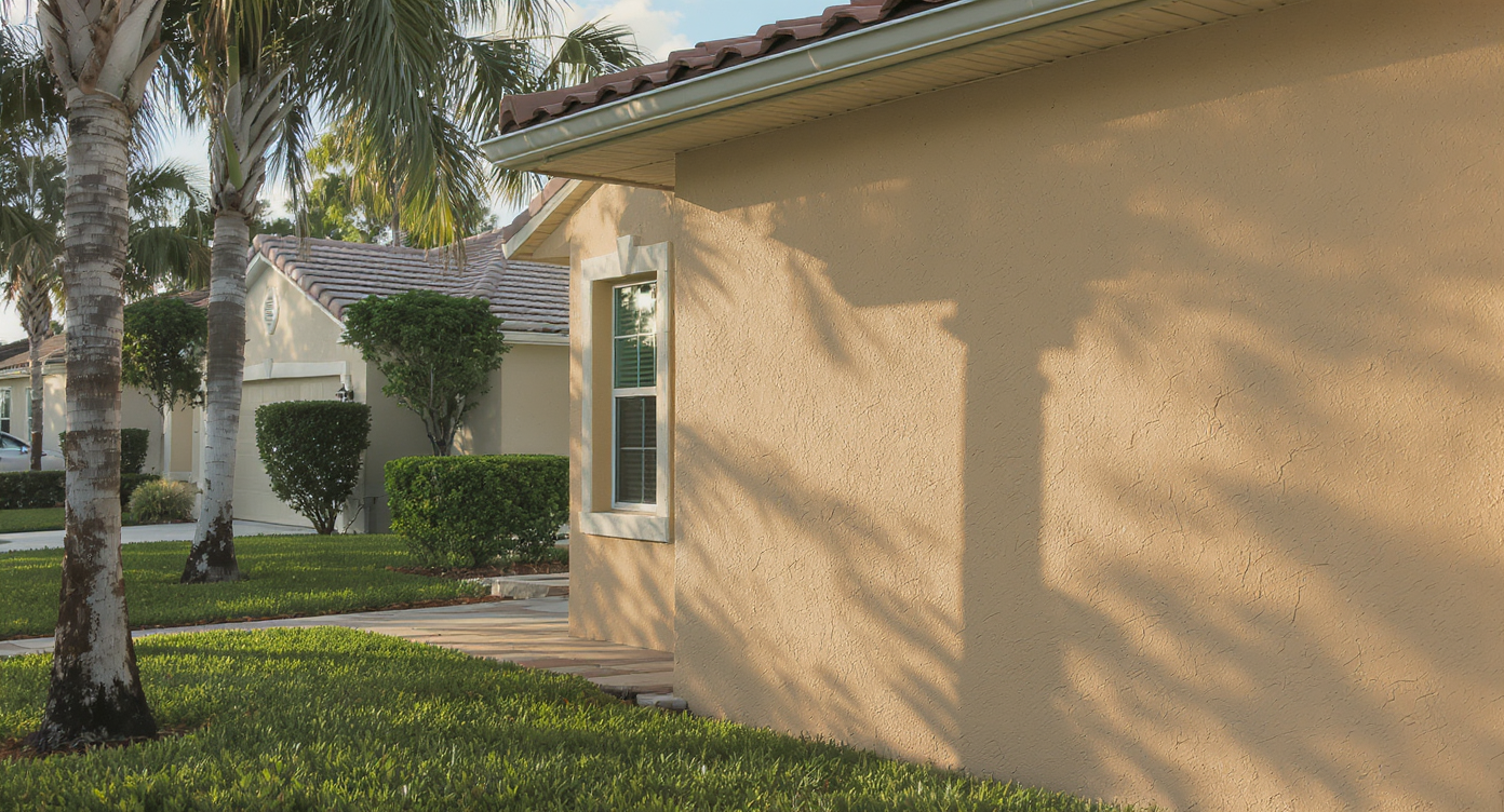 Freshly repaired stucco exterior on a St. Petersburg residential home with palm trees and paver walkway