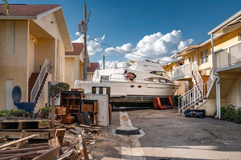 Storm-damaged residential roofs and displaced boat after hurricane in coastal neighborhood