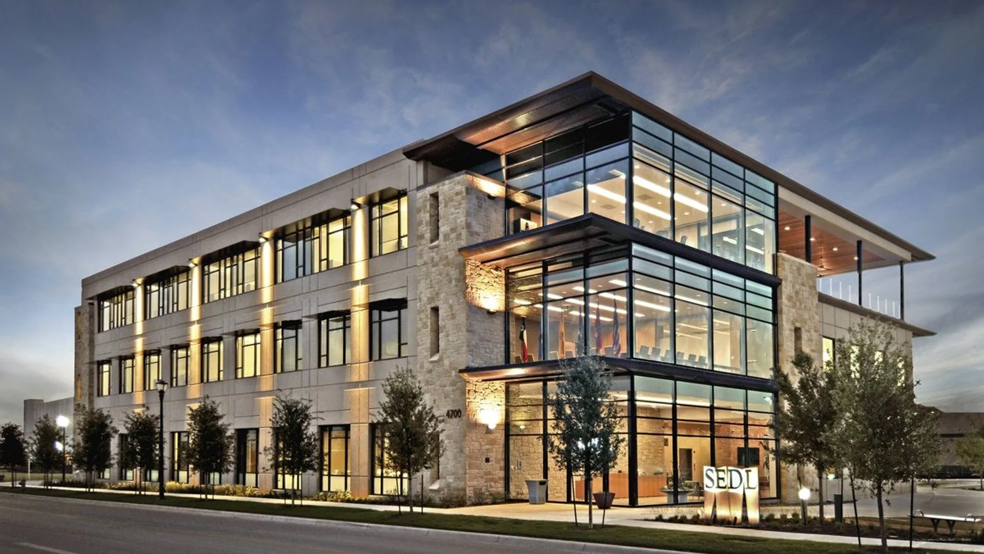 Modern commercial office building with flat roof and glass facade at dusk